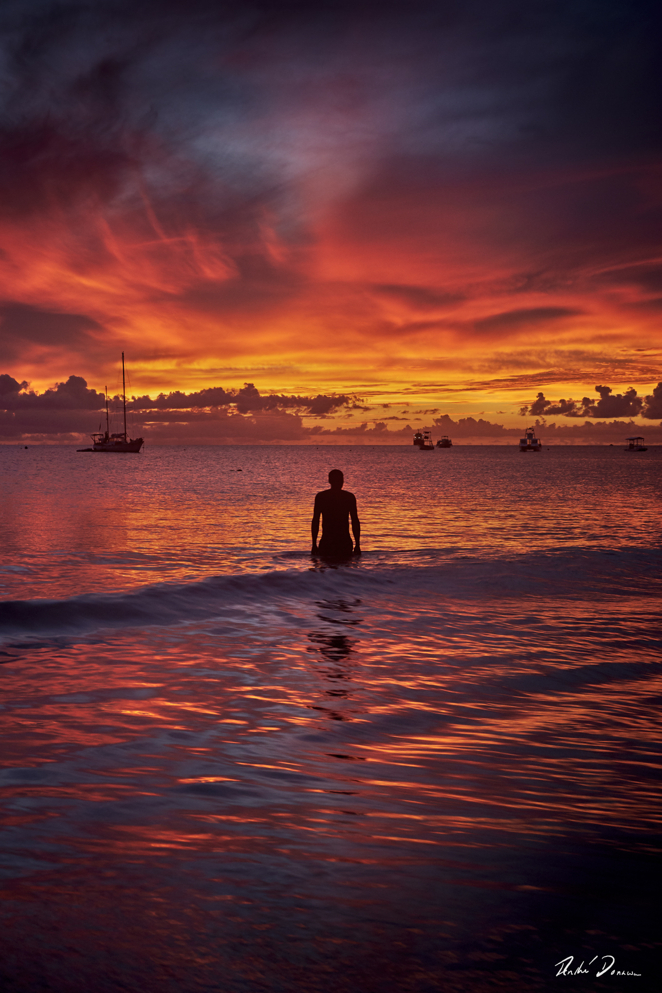 A man steps into the ocean during an explosive sunset, Brownes Beach Barbados