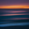 Abstract seascape created with Intentional Camera Movement photography during golden hour, featuring horizontal wave lines and a blurred ocean horizon